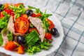 Fresh salad with chicken breast, arugula, black olives,red pepper, lettuce, fresh sald leaves and tomato on a white plate on woode Royalty Free Stock Photo