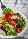 Fresh salad with chicken breast, arugula, black olives,red pepper, lettuce, fresh sald leaves and tomato on a white plate on woode Royalty Free Stock Photo