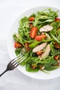 Fresh salad with chicken, tomato and greens (spinach, arugula) on white background top view