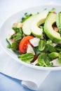Fresh salad with chicken, tomatoes, spinach and avocado on blue wooden background close up