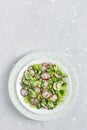 Fresh salad of cucumbers, radishes, green peas and herbs in white bowl.Vertical orientation. Top view Royalty Free Stock Photo