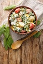 Fresh salad of eggs, potatoes, tomatoes and sorrel seasoned with cream sauce close-up in a bowl. Vertical top view