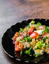 Fresh salad with fish, arugula, eggs,red pepper, lettuce, fresh sald leaves and tomato on a black plate on wooden table Royalty Free Stock Photo