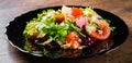 Fresh salad with fish, arugula, eggs,red pepper, lettuce, fresh sald leaves and tomato on a black plate on wooden table Royalty Free Stock Photo