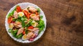 Fresh salad with fish, arugula, eggs,red pepper, lettuce, fresh sald leaves and tomato on a white plate on wooden table Royalty Free Stock Photo