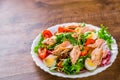 Fresh salad with fish, arugula, eggs,red pepper, lettuce, fresh sald leaves and tomato on a white plate on wooden table Royalty Free Stock Photo