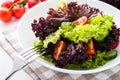 Fresh salad with green and purple lettuce, tomatoes and cucumbers on white wooden background close up. Royalty Free Stock Photo