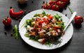 Salad with Green rucola, cheese, tuna, onion, pepper in white bowl on dark wooden background