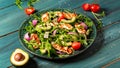 Fresh salad plate with arugula, halloumi cheese, tomatoes and avocado wooden background close up. Healthy food. Green meal