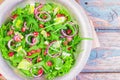 Fresh salad with pomegranate seeds, arugula, red onion, goat cheese, lemon slices, lettuce leaves, flavored with olive oil and