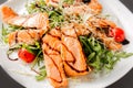 Fresh salad of salmon pieces, cherry tomatoes, lettuce, cheese and sauce on a white plate close up Royalty Free Stock Photo