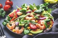 Fresh salad with shrimps, sweet corn, avocado, red tomatoes, lamb lettuce and onion on black table background. Top view Royalty Free Stock Photo