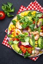 Fresh salad with shrimps, sweet corn, avocado, red tomatoes, lamb lettuce and onion on black table background. Top view Royalty Free Stock Photo