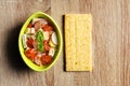 Fresh salad with tofu in bowl and corn crisp bread on wooden background.