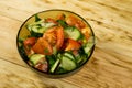 Fresh salad with tomato, cucumber, onion, parsley and dill in glass bowl on wooden table Royalty Free Stock Photo