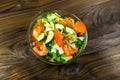 Fresh salad with tomato, cucumber, onion, parsley and dill in glass bowl on wooden table Royalty Free Stock Photo