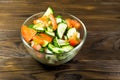 Fresh salad with tomato, cucumber, onion, parsley and dill in glass bowl on wooden table Royalty Free Stock Photo