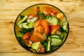 Fresh salad with tomato, cucumber, onion, parsley and dill in glass bowl on wooden table Royalty Free Stock Photo