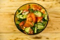 Fresh salad with tomato, cucumber, onion, parsley and dill in glass bowl on wooden table Royalty Free Stock Photo