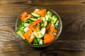 Fresh salad with tomato, cucumber, onion, parsley and dill in glass bowl on wooden table Royalty Free Stock Photo