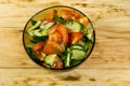 Fresh salad with tomato, cucumber, onion, parsley and dill in glass bowl on wooden table Royalty Free Stock Photo