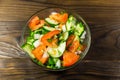 Fresh salad with tomato, cucumber, onion, parsley and dill in glass bowl on wooden table Royalty Free Stock Photo