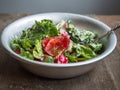 Fresh salad from tomatoes, cucumbers and aromatic herbs, dressed with sour cream in a deep aluminum bowl with a spoon, on an old Royalty Free Stock Photo