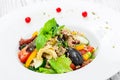 Fresh salad with tuna, arugula, artichokes, codfish, olives, basil, sun dried tomatoes, cherry tomatoes on wooden background