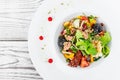 Fresh salad with tuna, arugula, artichokes, codfish, olives, basil, sun dried tomatoes, cherry tomatoes on wooden background