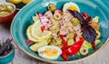 Fresh salad with tuna, olives, sweet peppers, eggs, fried potatoes, basil, lettuce and lemon on wooden background close up Royalty Free Stock Photo