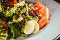 Fresh salad with vegetables, eggs and salmon served on white plate