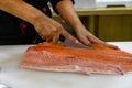 Fresh salmon fillet filleting or slicing on white cutting board table Royalty Free Stock Photo