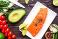 Fresh salmon fillet with lemon and dill on dark background