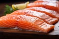 Fresh salmon fillets up close, resting on a wooden tabletop