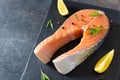 Fresh salmon steak with ingredients for cooking on a board on dark table. Raw trout steak with salt, pepper, lemon and rosemary on Royalty Free Stock Photo