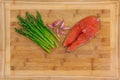 Fresh salmon steak surrounded with garlic and asparagus on a wooden cutting board Royalty Free Stock Photo