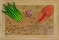 Fresh salmon steak surrounded by pink peppercorns, Himalayan salt, garlic and asparagus on a wooden cutting board Royalty Free Stock Photo