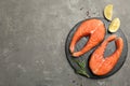 Fresh salmon steaks with spices, lemon and rosemary on grey table. Space for text Royalty Free Stock Photo