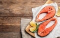 Fresh salmon steaks with spices, lemon and rosemary on wooden table. Space for text Royalty Free Stock Photo