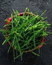 Fresh samphire in a red bowl on black background