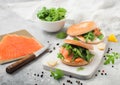 Fresh sandwiches with bagel and salmon, cream cheese and wild rocket on white board with smoked salmon pack and knife