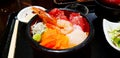 Fresh sashimi with salmon, tuna sliced, prawn and wasabi in black bowl on tray at Japanese restaurant. Royalty Free Stock Photo