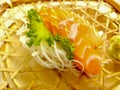 Fresh sashimi salmon with wasabi and lettuce served in a woven rattan dish