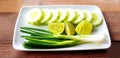 Fresh Scallion, sliced cucumber and lime or lemon in white plate on wooden table Royalty Free Stock Photo