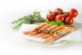 Fresh scampi, also called Norway Lobster or langoustine, on a plate with paper towel, herbs and tomatoes, ready to cook an
