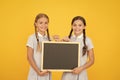 Fresh school information copy space. School news. True information. Little girls hold writing surface yellow background