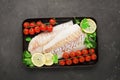 Fresh sea food fish cod white fish before baking on a baking sheet with fresh cherry tomatoes, lemon slices, fresh