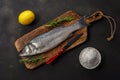 Fresh seabass fish with rosemary and sea salt on black table. Seafood concept