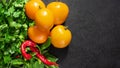 Fresh seasonal vegetables: yellow tomatoes, parsley, basil, red chili pepper on black background. Top view. Copy space Royalty Free Stock Photo