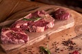 Fresh, seasoned Ribeye steak on a cutting board with pepper, rosemary, sun-dried tomatoes. Next to a glass of red wine. Royalty Free Stock Photo